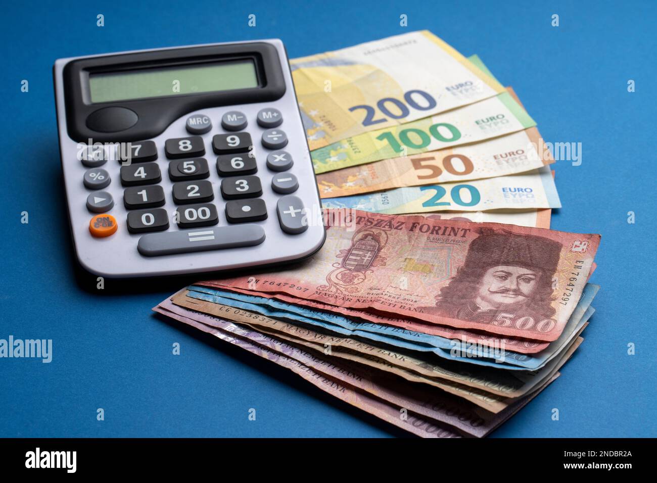 There are Hungarian forints and euro banknotes on a flat surface. Next to  it is a calculator on a blue table. HUF EUR exchange rate Stock Photo -  Alamy