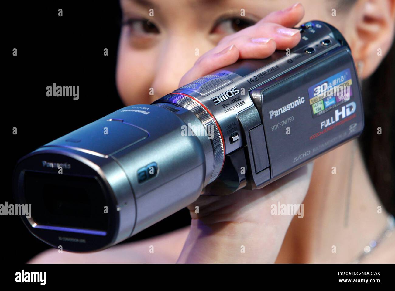 A model shows Panasonic's digital camcorder SDT750, right, capped with a  3-D conversion lens, during a press unveiling in Tokyo, Wednesday, July 28,  2010. The whole camcorder and lens setup starts at