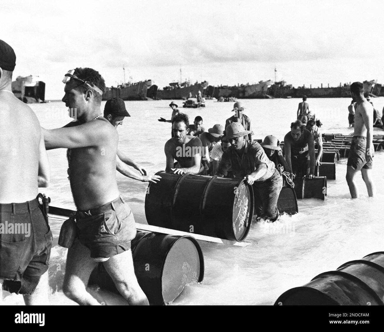 United States Marines and Navy Seabees roll drums of gasoline and fuel ...