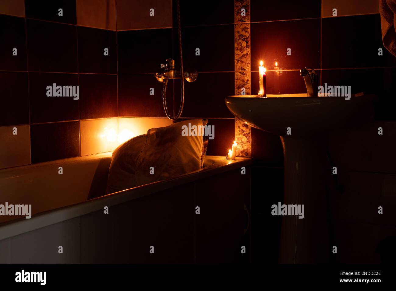 Bathroom as a shelter from rocket attacks in Ukraine by candlelight with a bed in the bathroom without light, war, sleeping in the bathroom Stock Photo