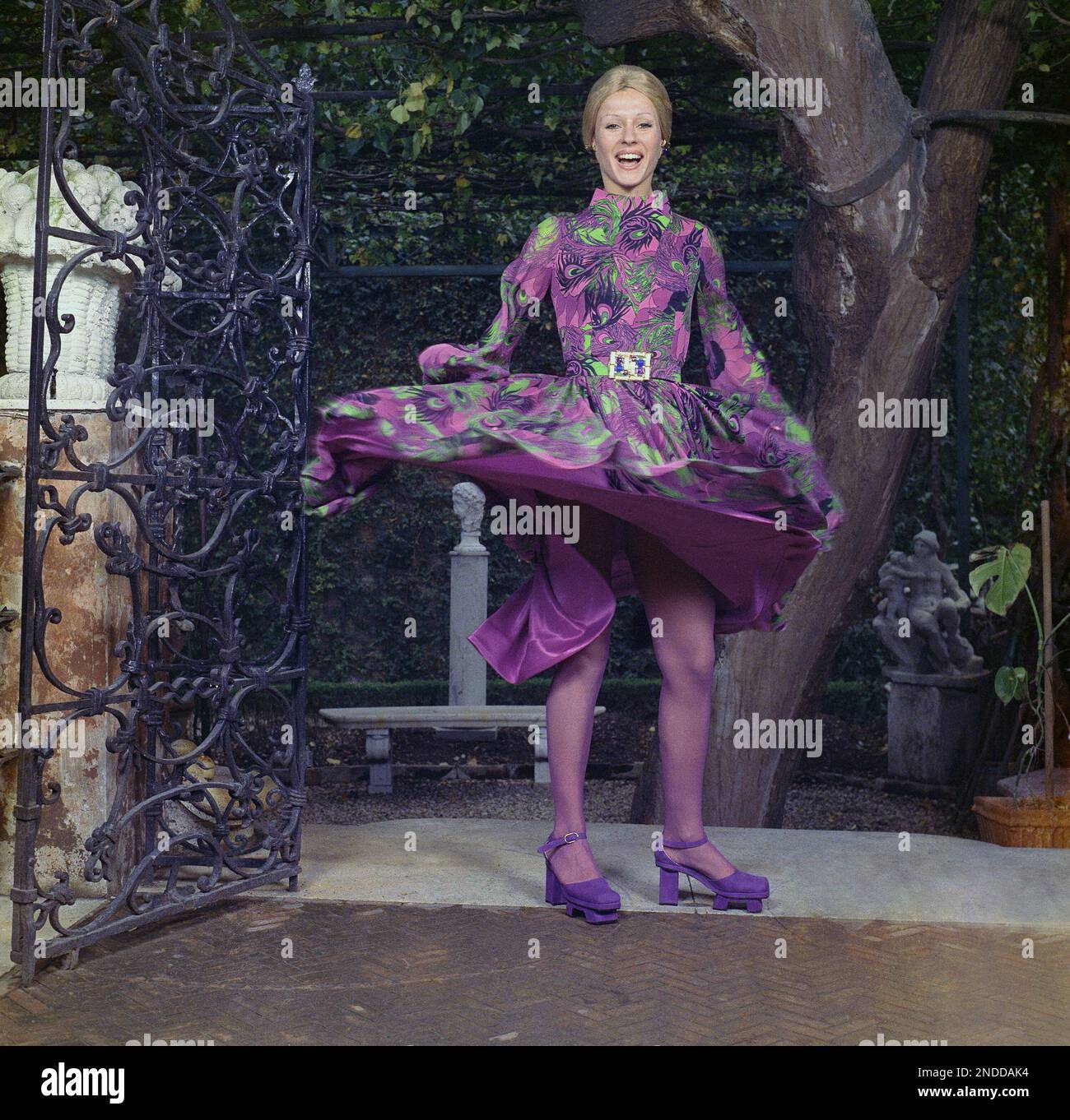 Silk jersey dress with down pleats opening into flairs below waist featuring La Mendola's print 'Canton' in deep royal purple, violet and jade green, April 13, 1971. Purple satin laces latch up Silk jersey dress with down pleats opening into flairs below waist featuring La Mendola's print 'Canton' in deep royal purple, violet and jade green, April 13, 1971. Purple satin laces latch up
