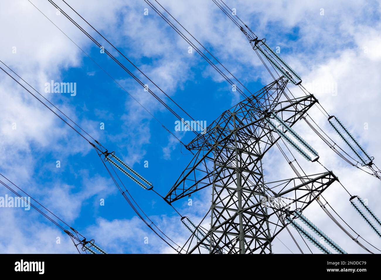 High-voltage pylon against a blue sky with a slight cloud cover. High voltage transmission lines silhouette Stock Photo