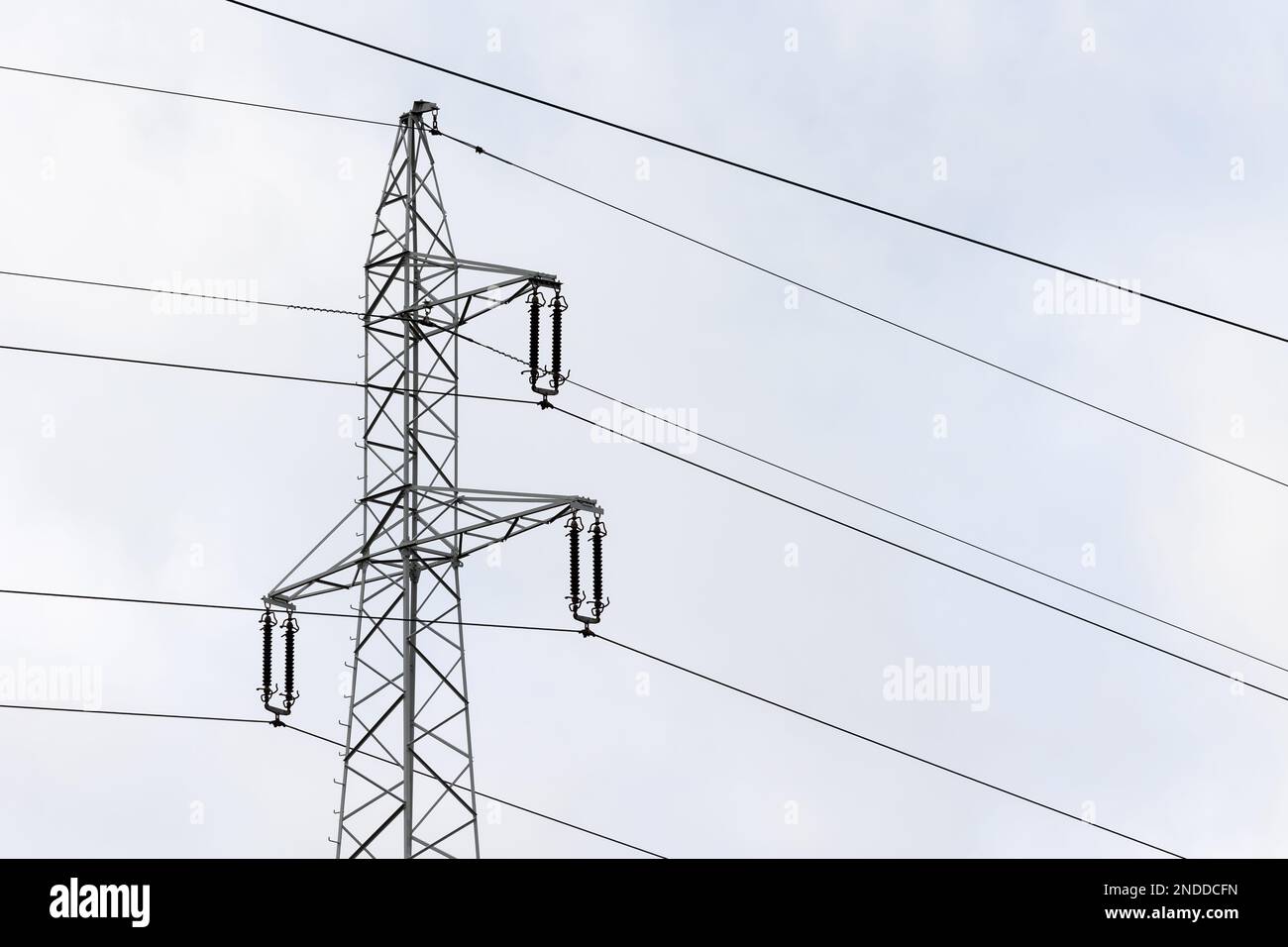 The silhouette of a high-voltage pylon against a completely cloudy sky. Development of high-voltage transmission networks Stock Photo