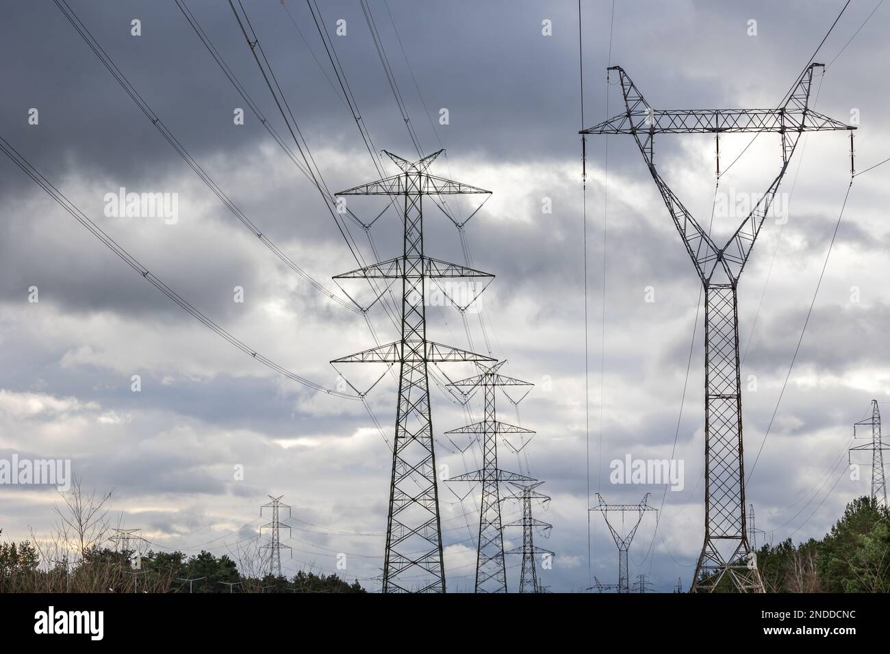 The silhouette of a high-voltage pylon against a dramatically cloudy sky. Development of high-voltage transmission networks Stock Photo