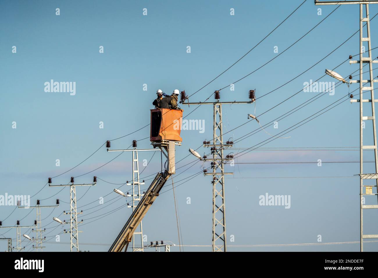 Electrical workers are making a high voltage connection. Electricity poles and cables. Stock Photo