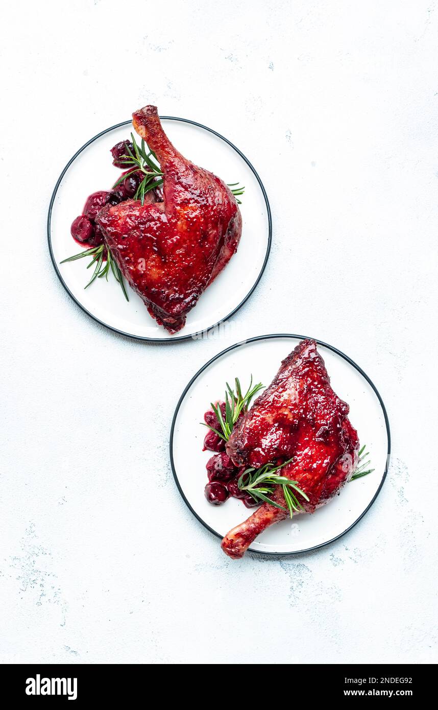 Baked duck legs in cherry red wine sauce with rosemary. Delicacy dinner