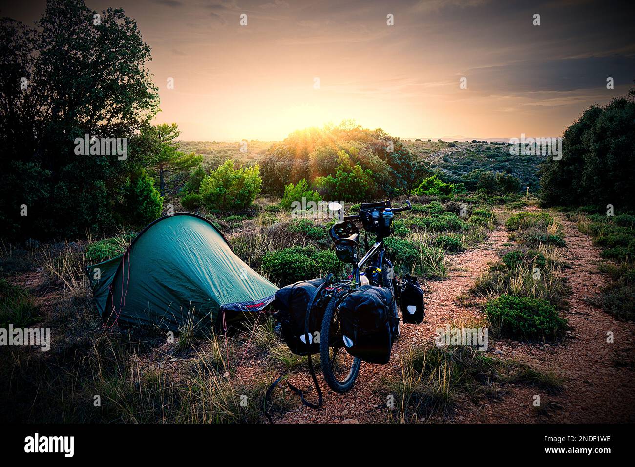 Bivouac site with tent and touring bike in the hills of Gargallo at sunset Stock Photo