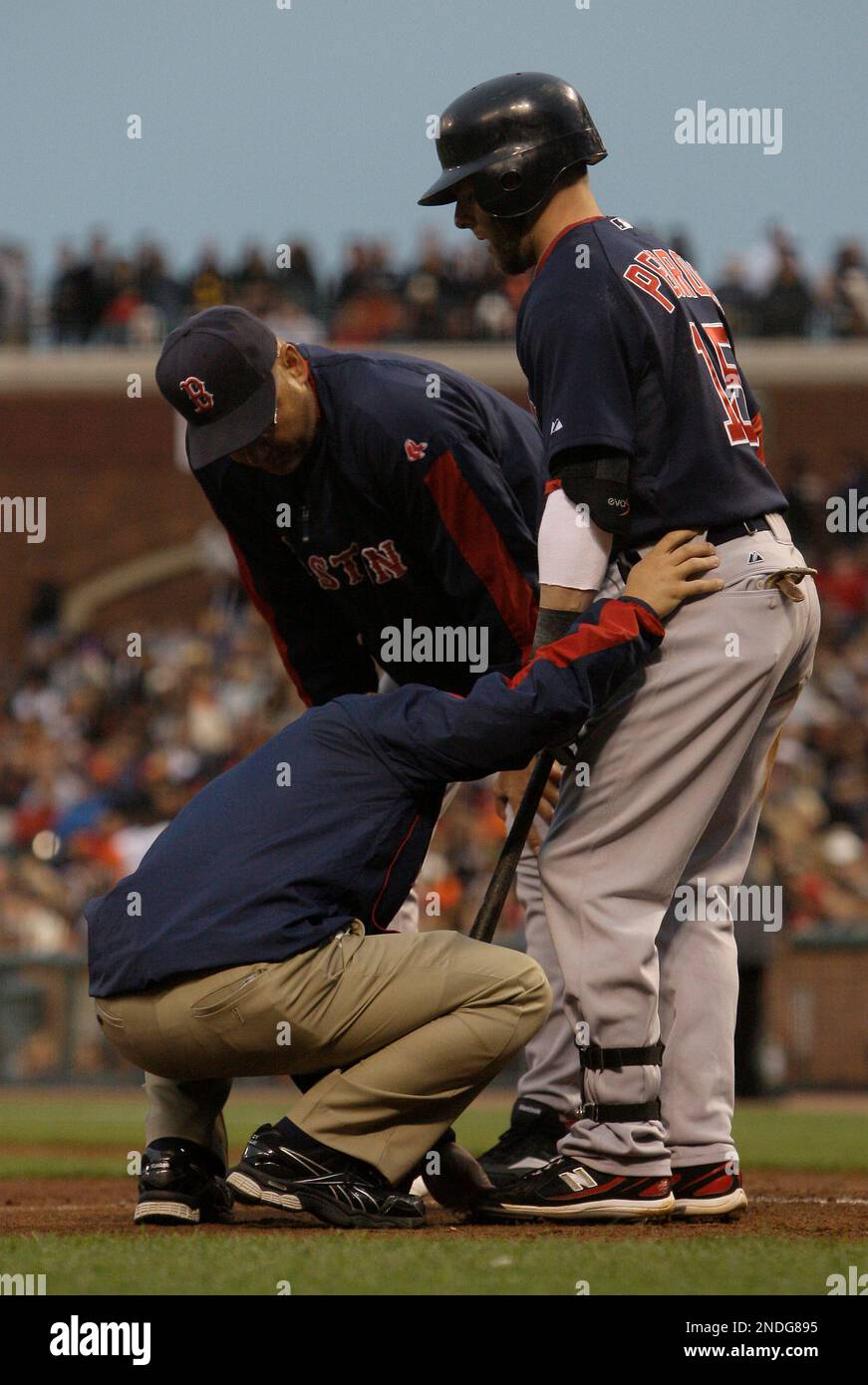 Boston Red Sox's Dustin Pedroia, right, is tended to by a trainer, left