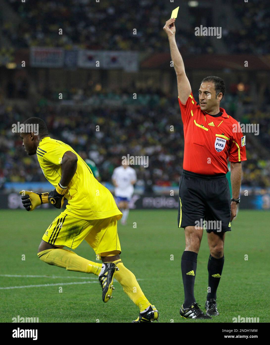 Referee Olegario Benquerenca, from Portugal, right, shows a yellow card to Nigeria goalkeeper