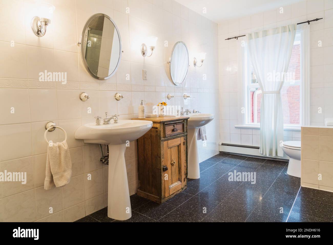 His and her pedestal sinks between old wooden vanity in main bathroom