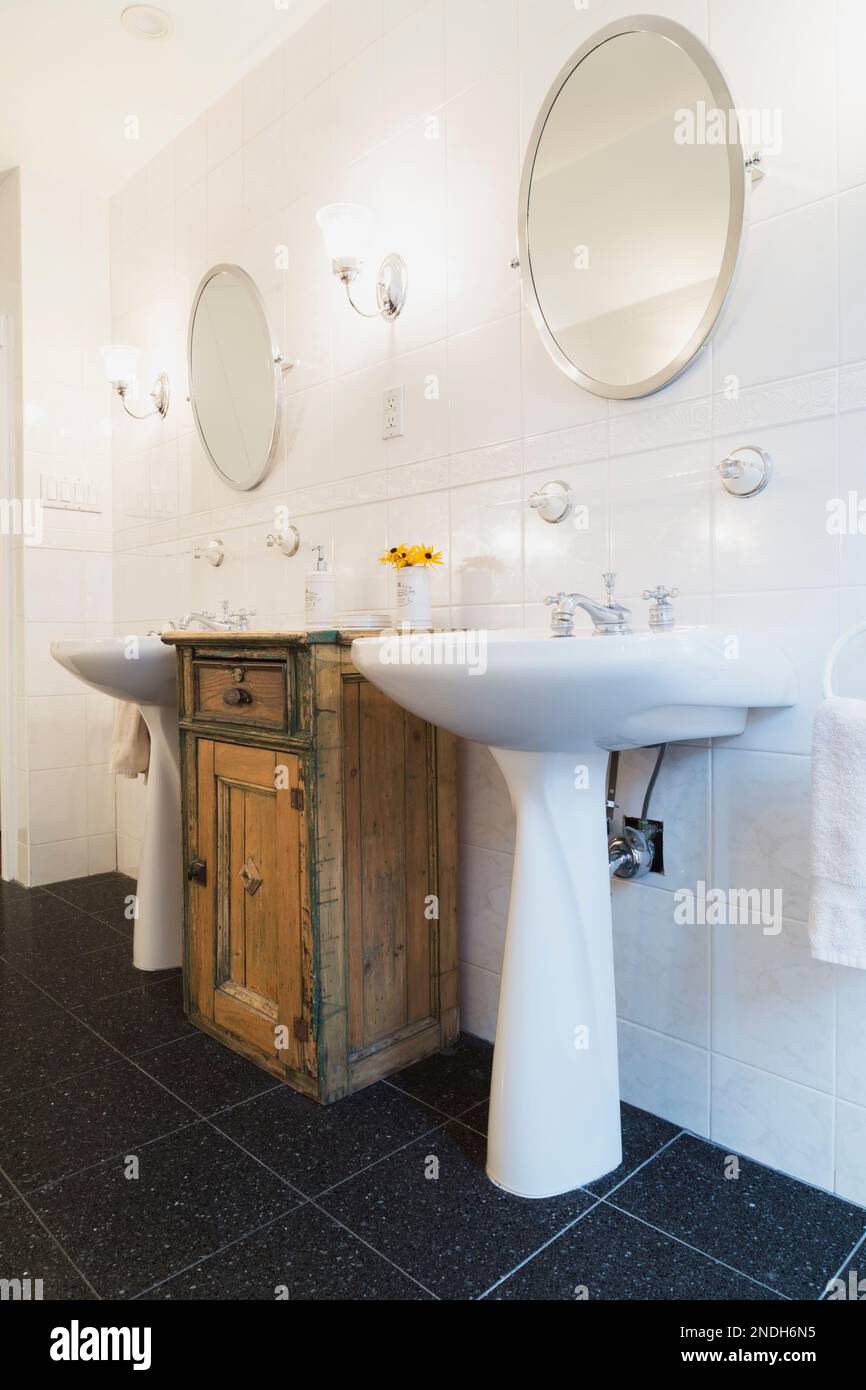 His and her pedestal sinks between old wooden vanity in main bathroom