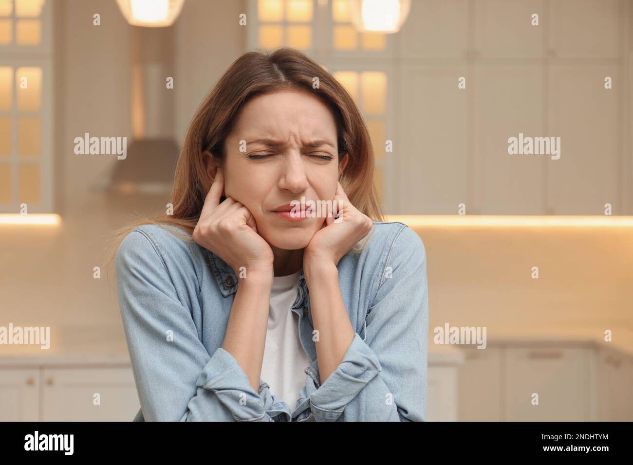 Emotional young woman covering her ears with fingers at home Stock