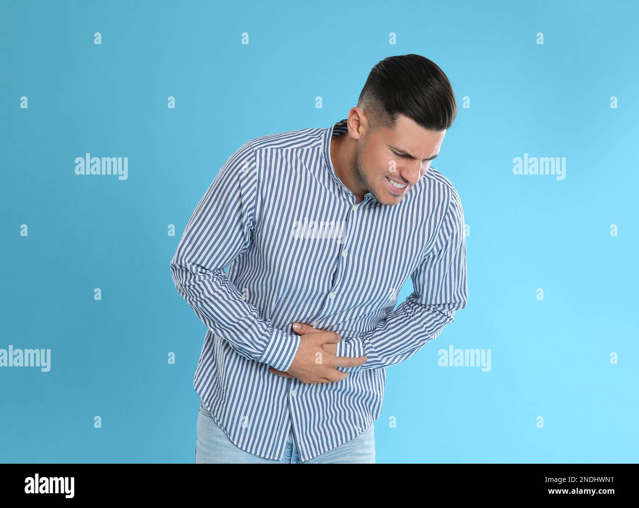 Man suffering from stomach ache on light blue background. Food