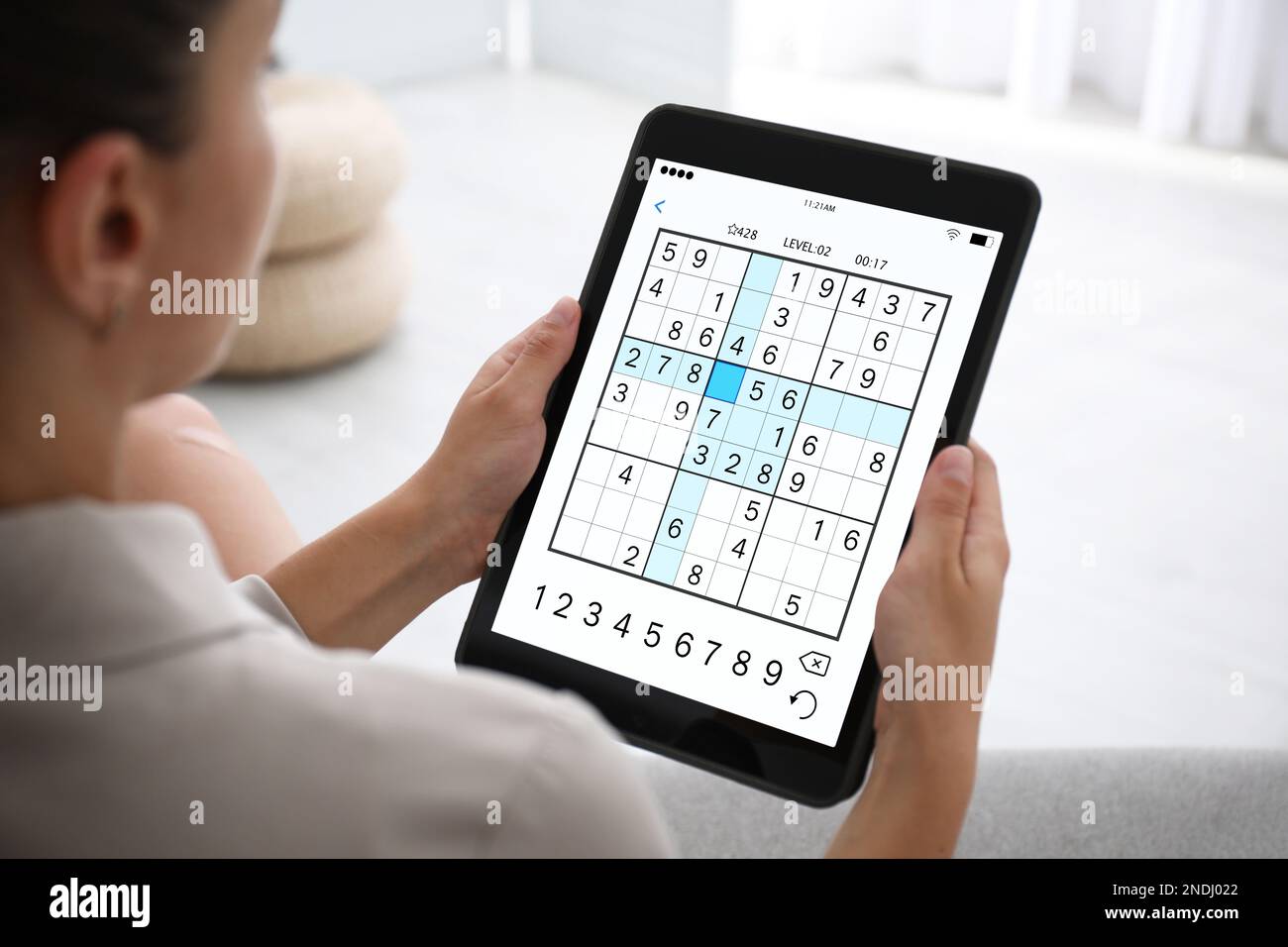 Woman playing sudoku game on tablet indoors, closeup Stock Photo
