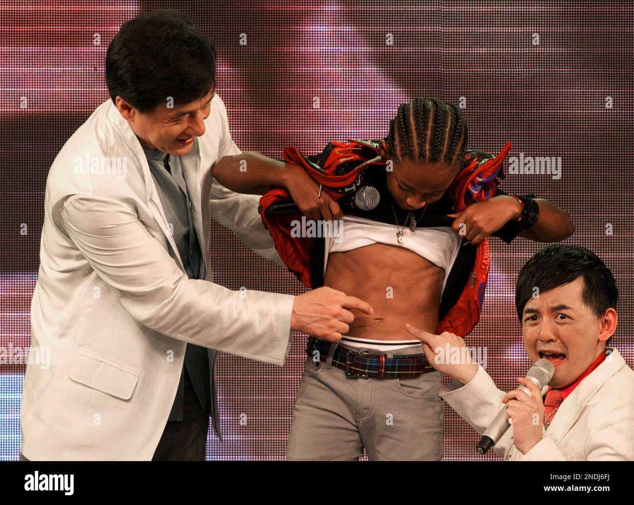 An emcee, right, reacts while Jaden Smith, son of U.S. actor Will Smith,  center, shows his muscles while Hong Kong actor Jackie Chan looks on at the  premiere of their new movie \, image size:1300x1036