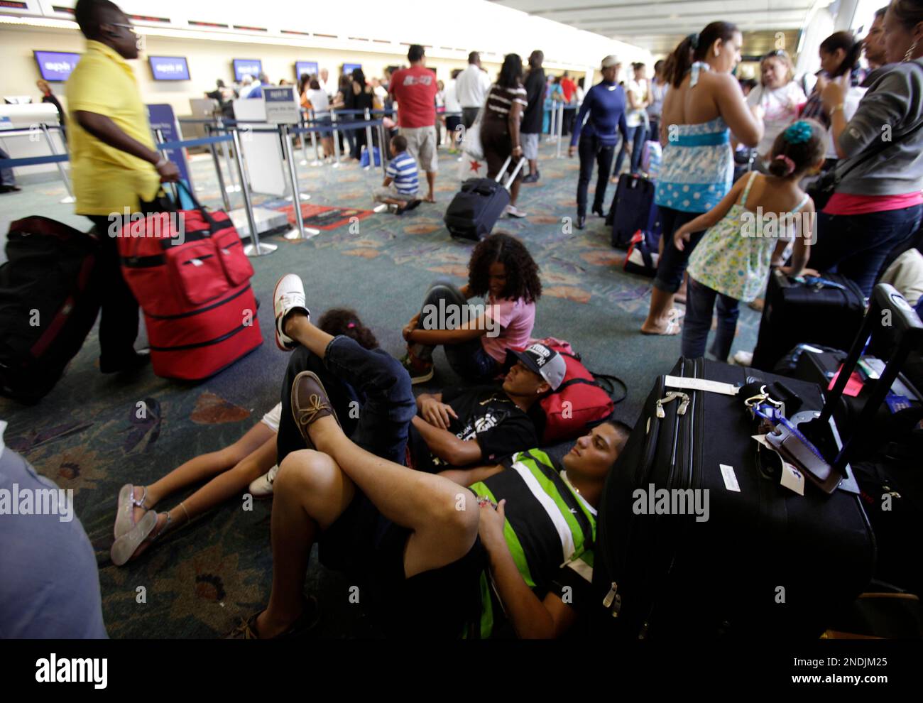 Robert Aviles, right, and Jose Valentin, left, of Puerto Rico, lie on the floor with their luggage at the Fort Lauderdale-Hollywood International Airport in Fort Lauderdale, Fla. Sunday, June 13, 2010. Spirit Airlines canceled all of its flights through Tuesday, stranding thousands of passengers as the pilot's strike continues into its second day. (AP Photo/Lynne Sladky) Stock Photo