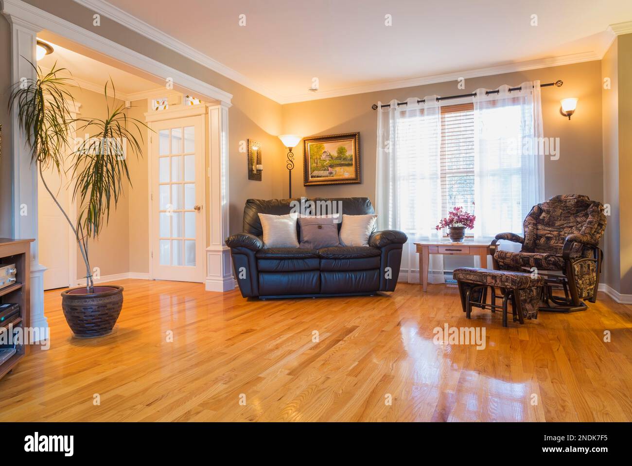 Black leather sofa and reclining armchair in living room with oak wood
