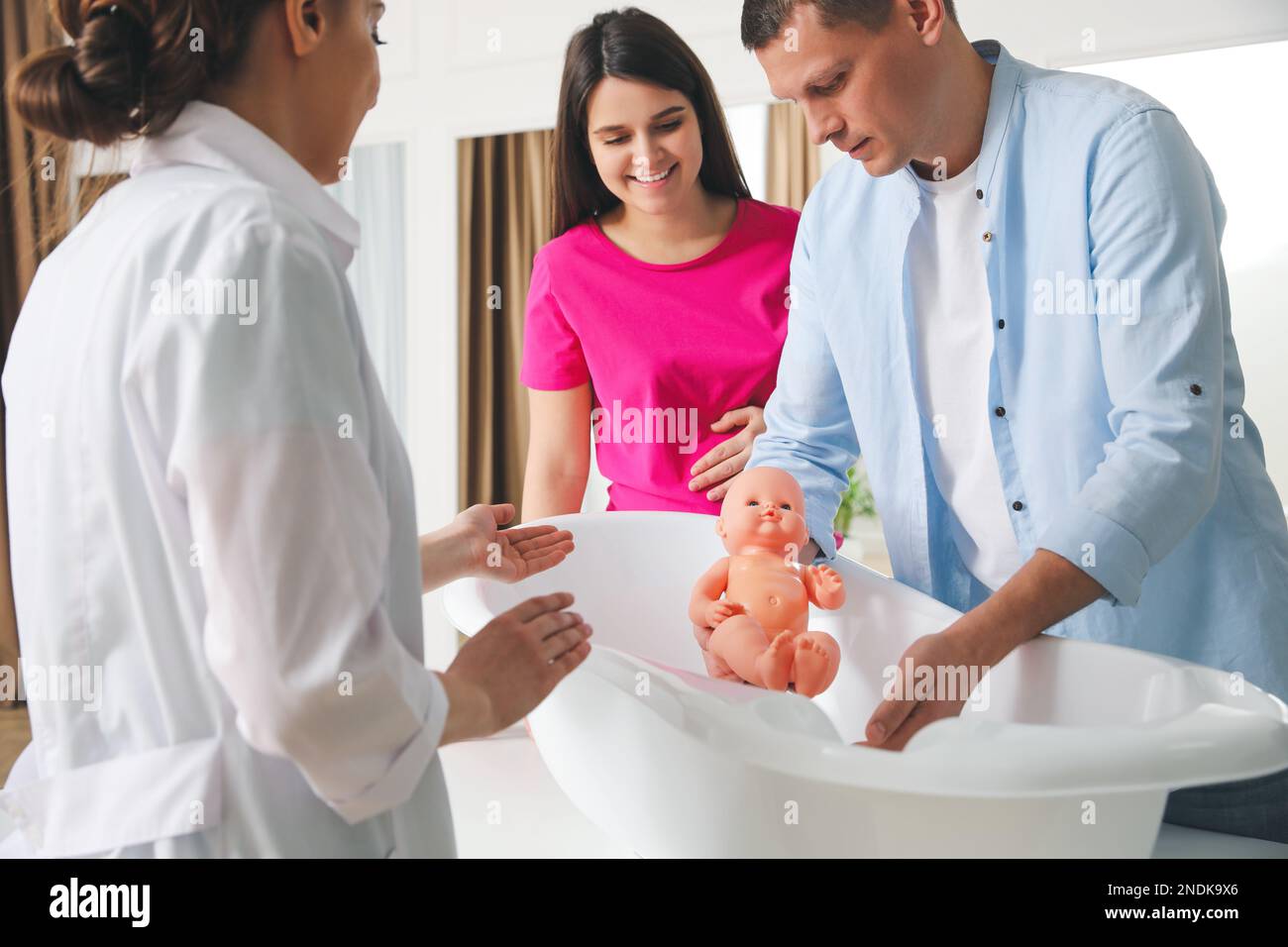 Man with pregnant wife learning how to bathe baby at courses for