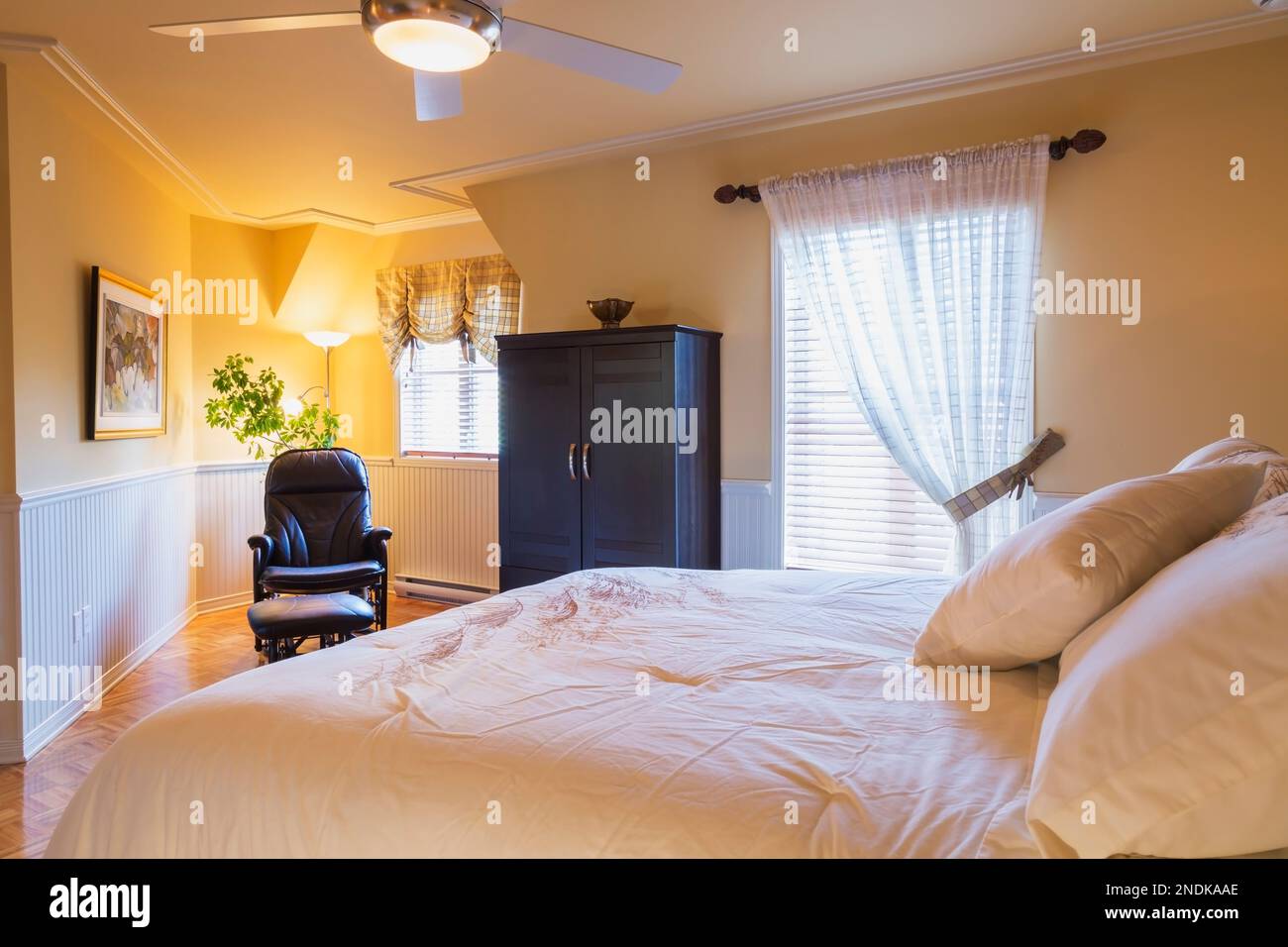 Queensize bed, wooden armoire and leather reclining armchair in