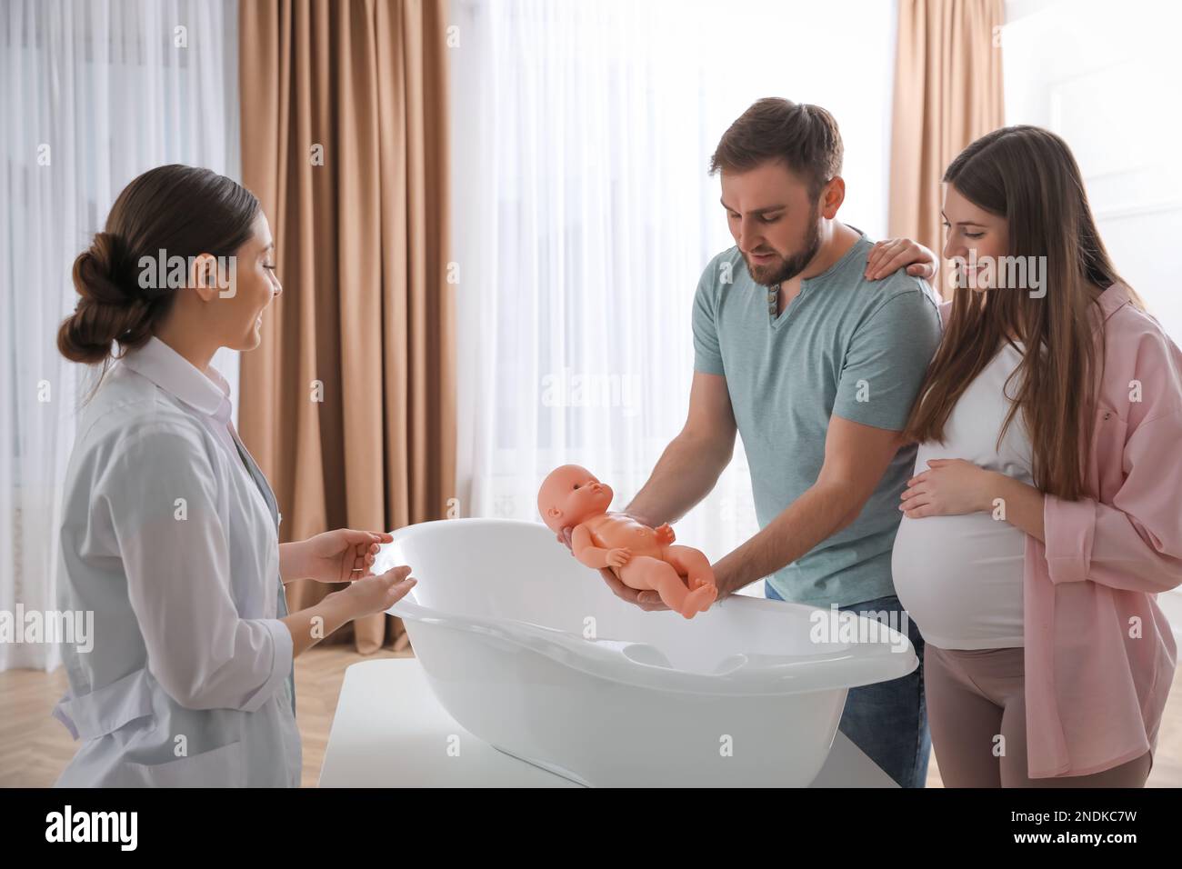 Man with pregnant wife learning how to bathe baby at courses for