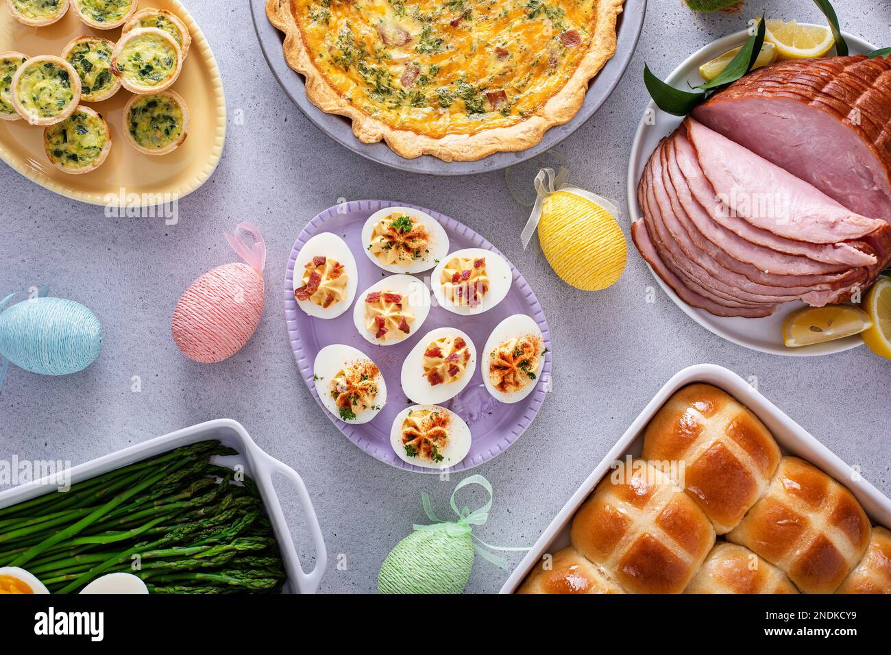Easter brunch table with ham, quiche, hot cross buns and deviled eggs