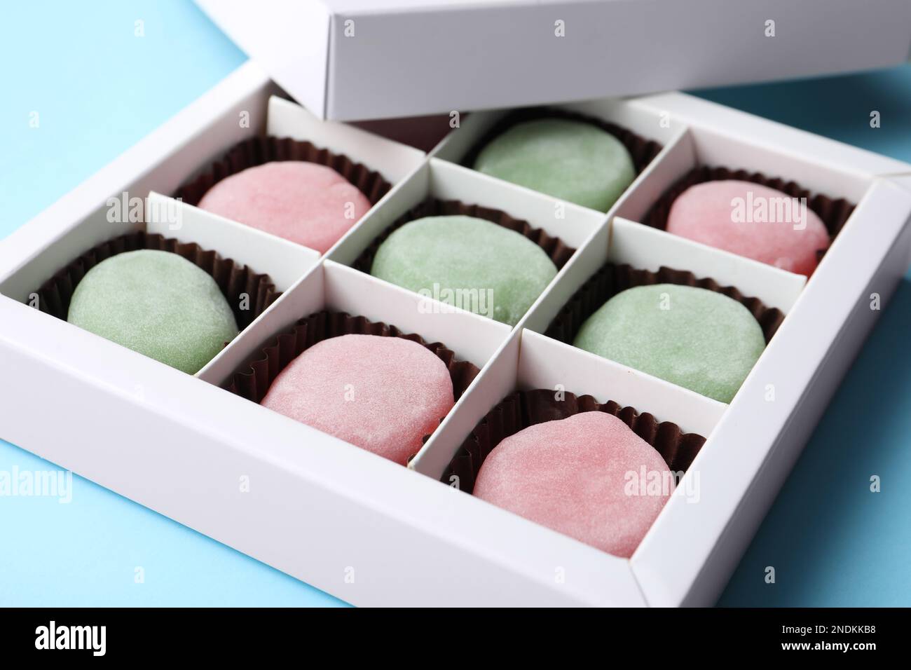 Many different delicious mochi in box on light blue background, closeup ...