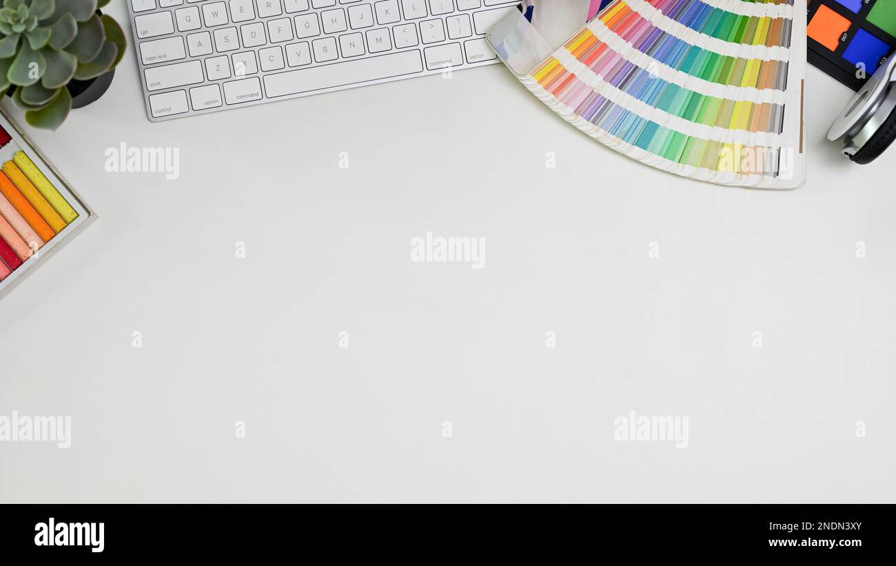 Top view of a minimal white graphic designer's desk with accessories and copy space. computer keyboard, color palette chart, color checker. Stock Photo