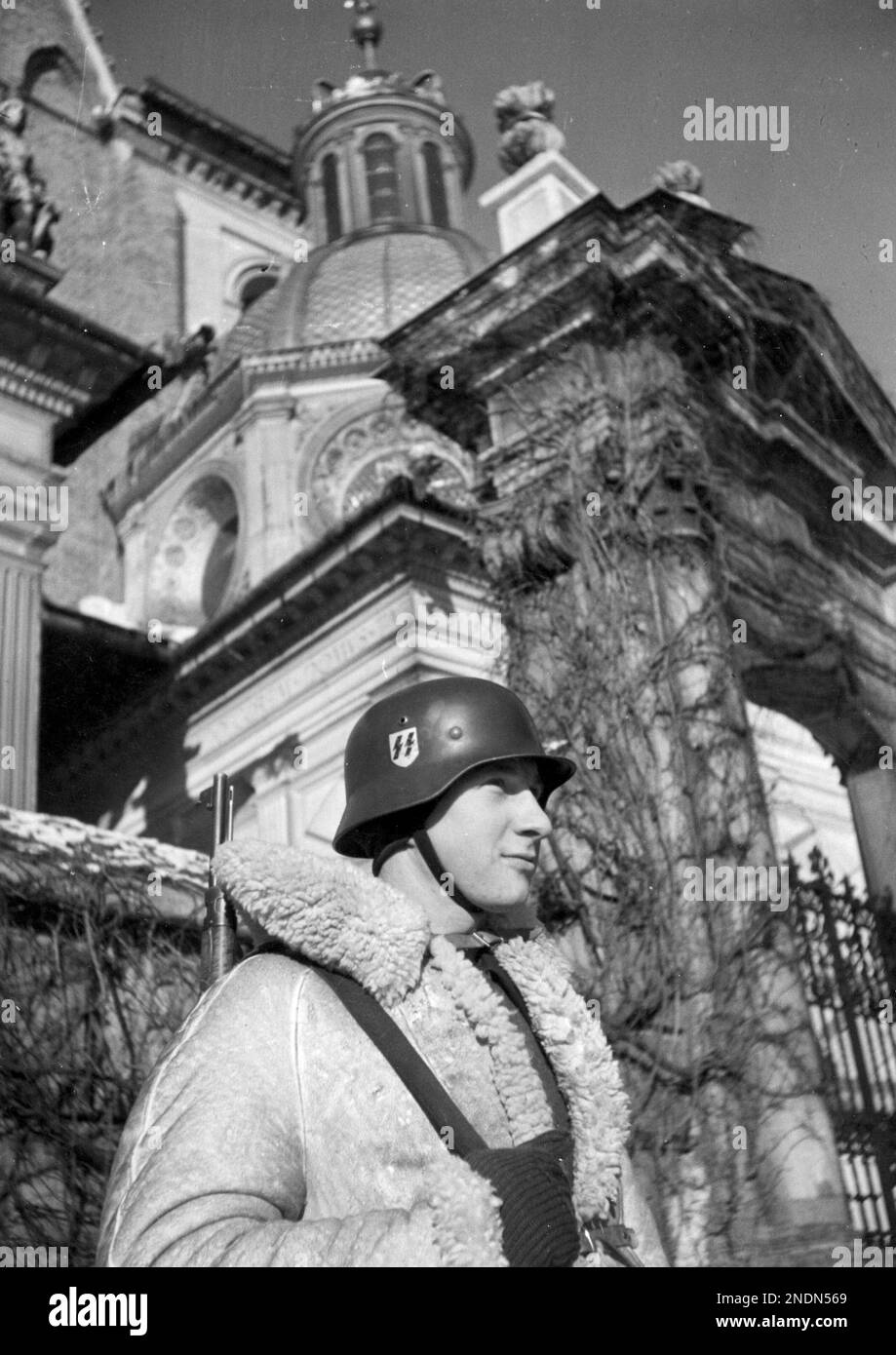 A soldier from the 10th SS Totenkopf regiment (wearing a sheepskin coat) on guard in front of Wawel Cathedral. SourceNac.gov.pl Stock Photo
