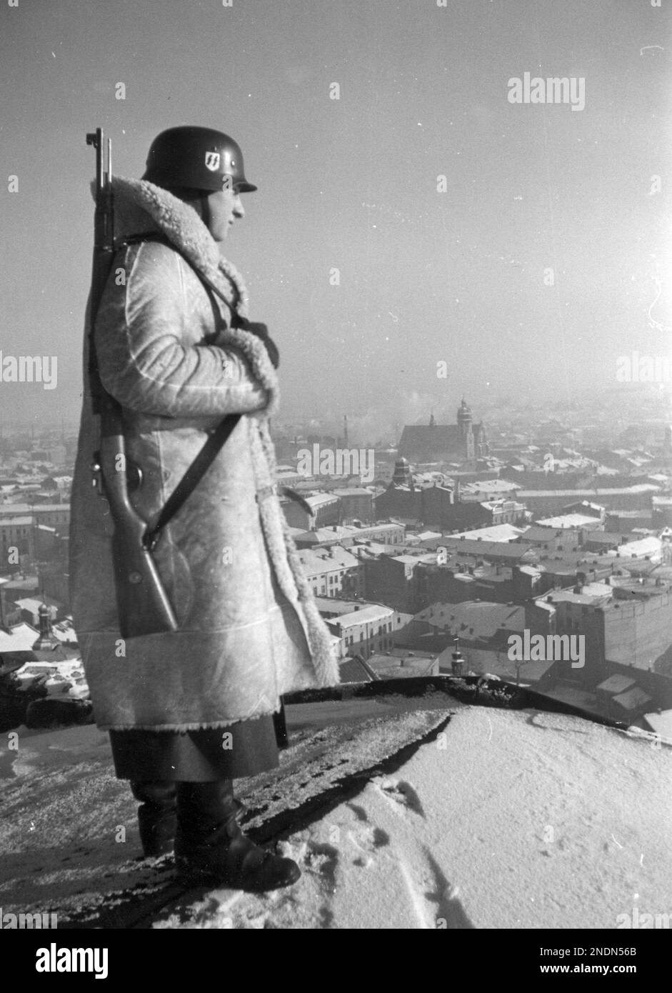 A soldier from the 10th SS Totenkopf regiment (wearing a sheepskin coat) on guard duty on the roof of the Royal Castle in Krakow. SourceNac.gov.pl Stock Photo