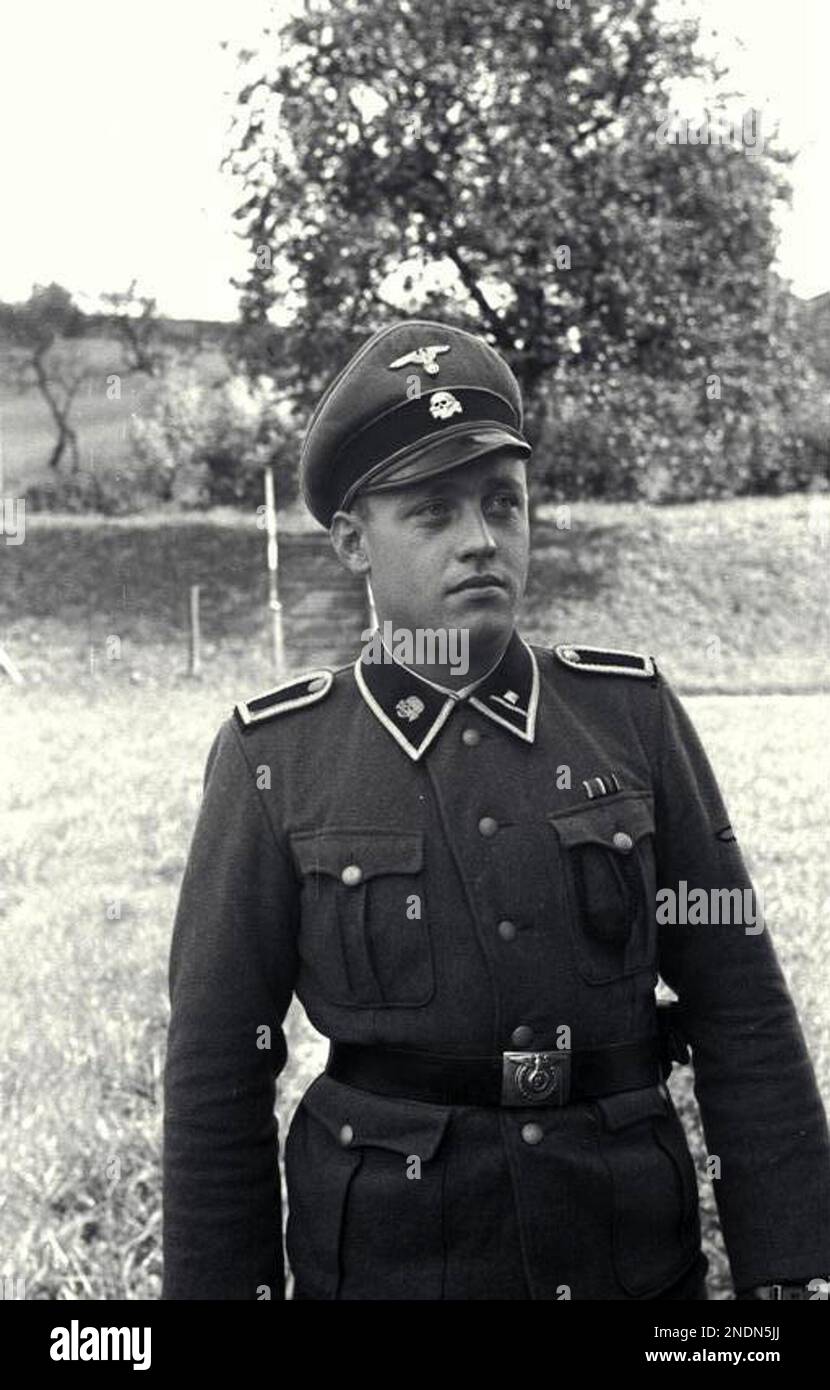 An officer of the SS totenkopf poses for a photo at Mauthausen concentration camp. The Totenkopf guards unit were a separate unit within the SS and were responsible for the running of the concentration and extermination camps. They are distinguished by the death's head emblem on their lapel. The 3rd SS Panzer division carried the name Totenkopf but were a fighting unit not involved in the administration of the camps. Photo Bundesarchiv, Bild 192-025 / CC-BY-SA 3.0, CC BY-SA 3.0 de, https://commons.wikimedia.org/w/index.php?curid=5485423 Stock Photo