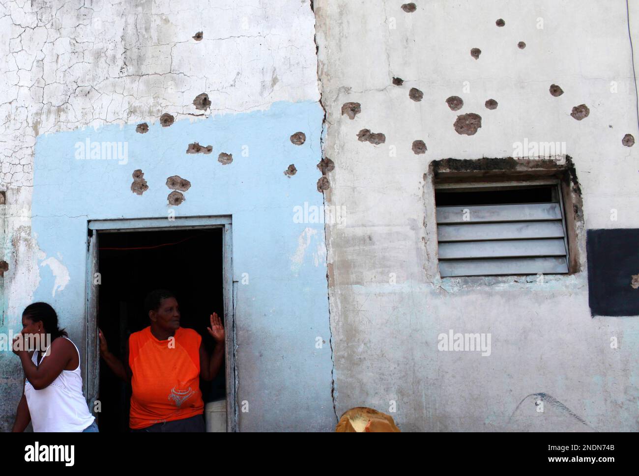 Residents gather outside their bullet-riddled home during a media tour ...