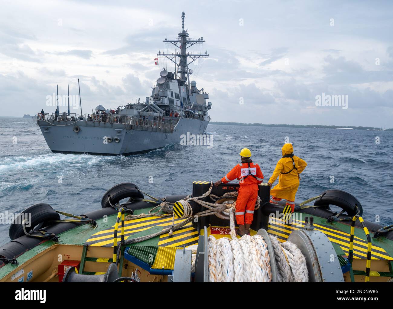 DIEGO GARCIA, British Indian Ocean Territory -- Tugboat operators watch as the Arleigh Burke-class guided-missile destroyer USS Paul Hamilton (DDG 60) arrives in Diego Garcia for a scheduled port visit date. The visit underscored the strategic importance of Diego Garcia to an enduring free and open Indo-Pacific by enabling presence, assuring access, and providing defense to the global commons. Paul Hamilton, part of the Nimitz Carrier Strike Group, is in U.S. 7th Fleet conducting routine operations.  (U.S. Navy photo by Mass Communication Specialist 2nd Class Jesus O. Aguiar) Stock Photo