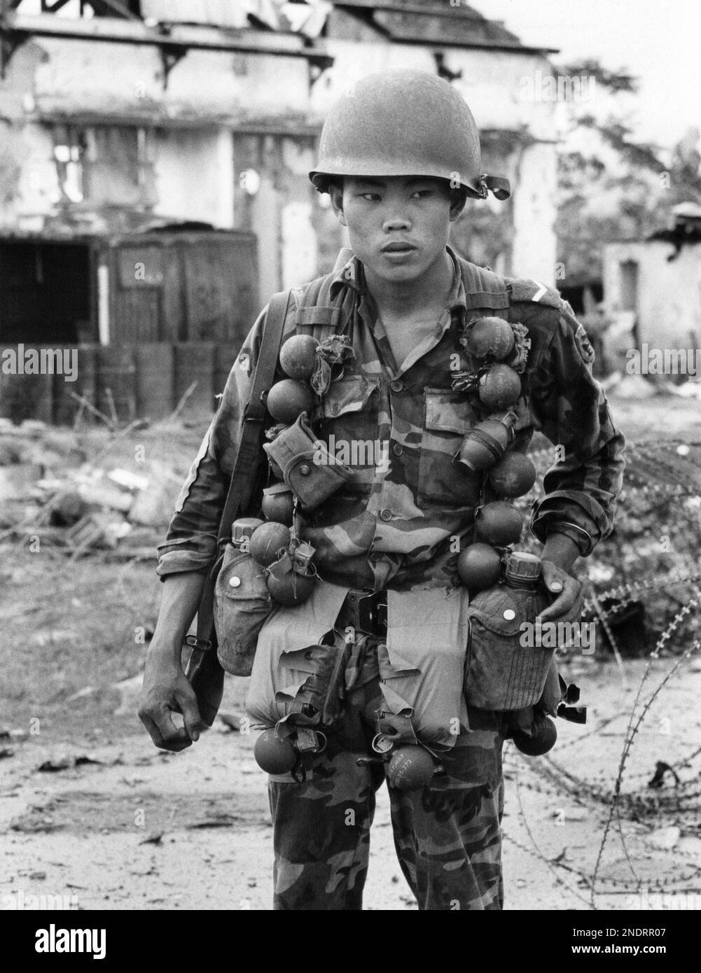 A South Vietnamese ranger, loaded with grenades, walks down the streets ...