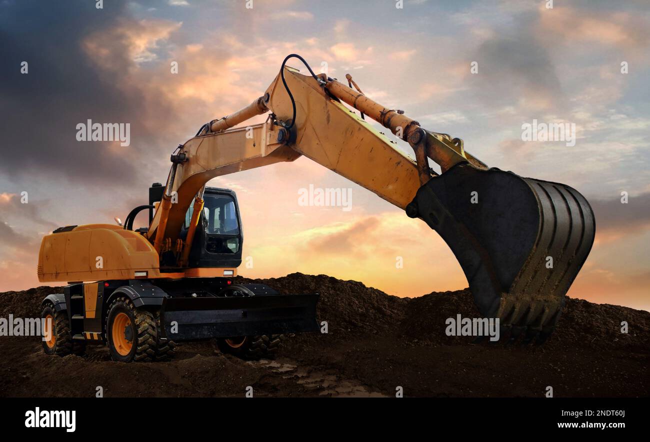 wheeled excavator at work digging soil during sunset Stock Photo - Alamy