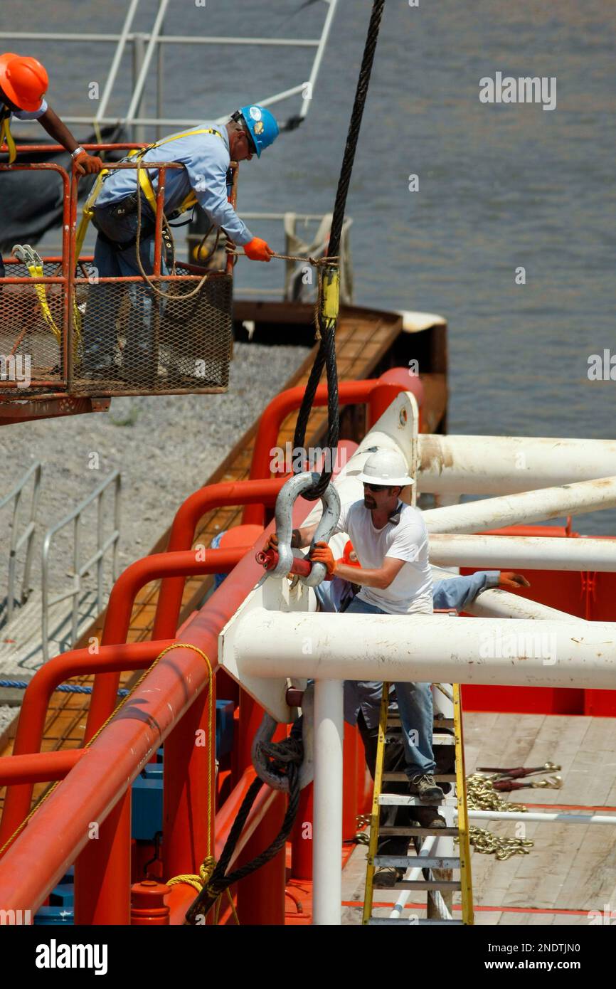Workers secure rigging for the containment vessel that will be used to ...