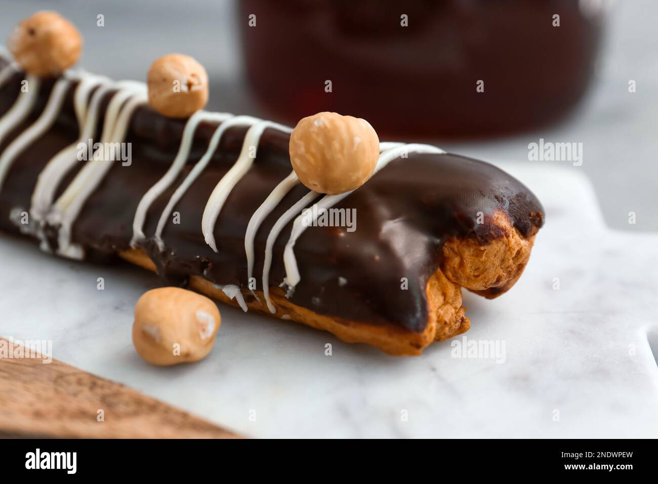 Board with delicious chocolate eclair and hazelnuts on grey table Stock Photo