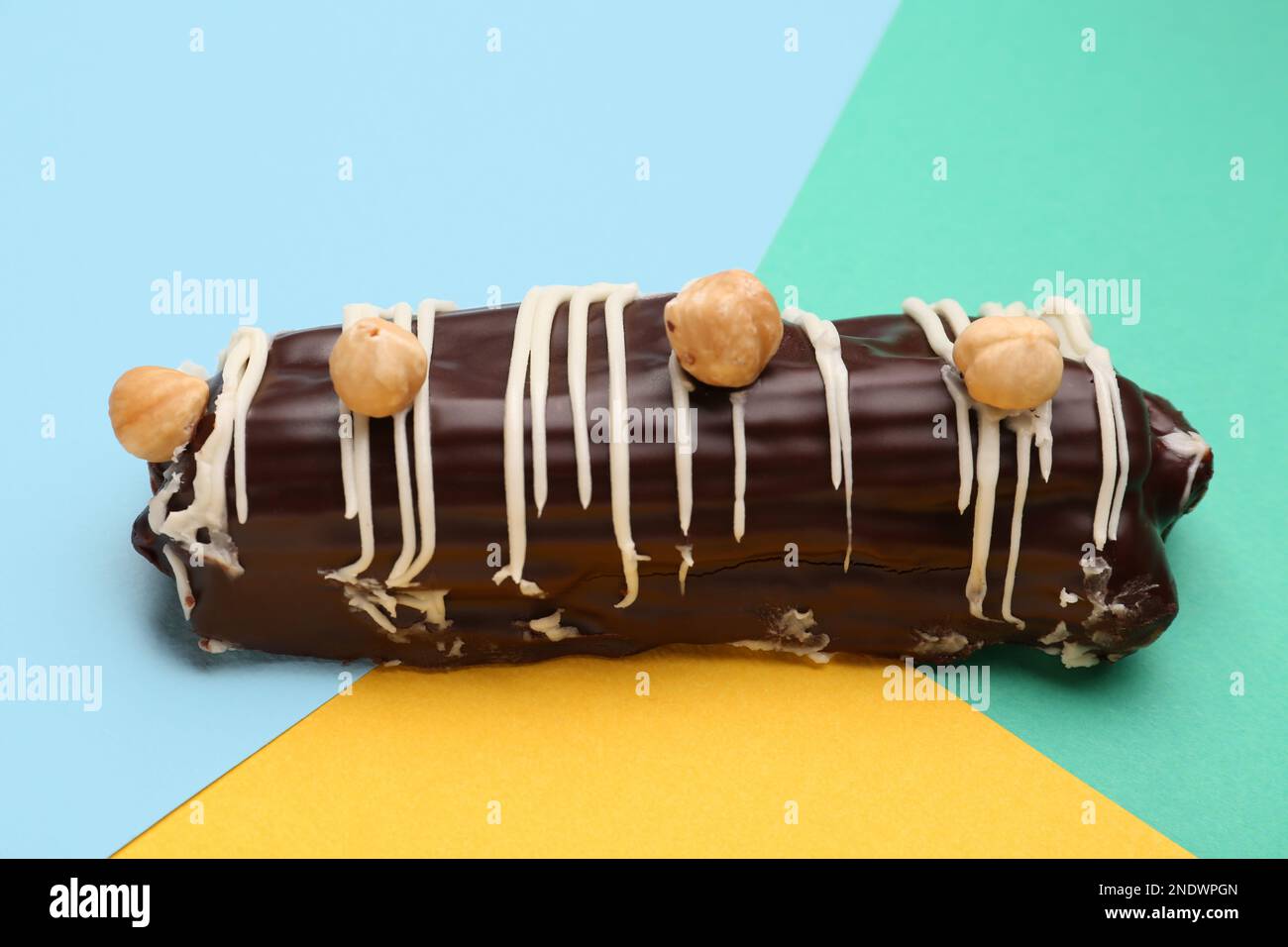 Delicious chocolate eclair with hazelnuts on colorful background Stock Photo