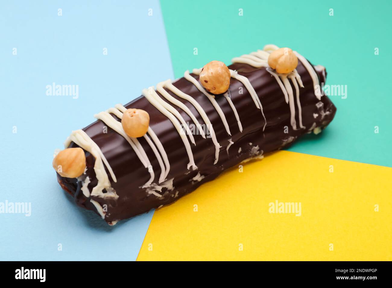 Delicious chocolate eclair with hazelnuts on colorful background Stock Photo