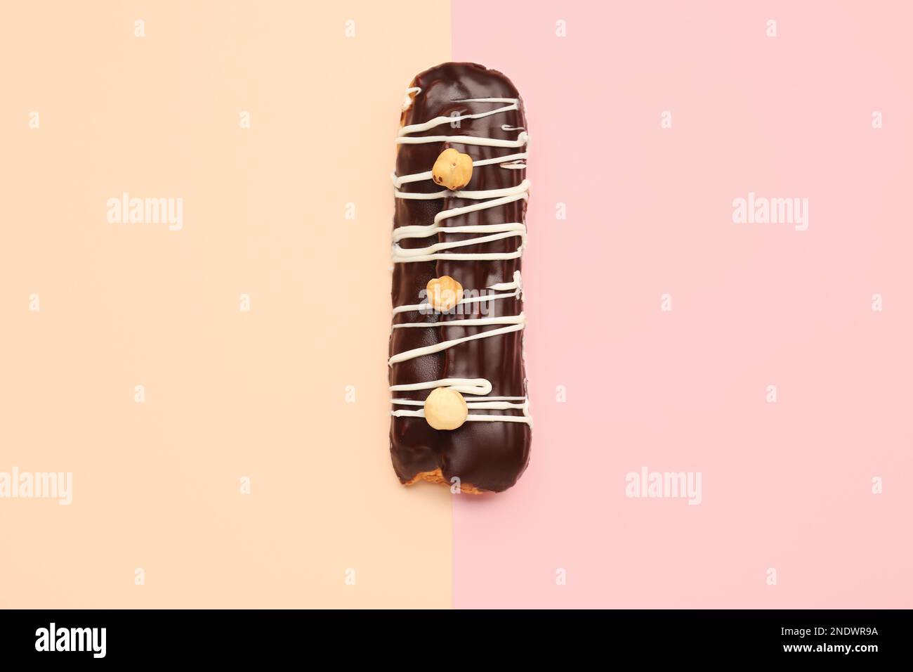 Tasty chocolate eclair on yellow and pink background Stock Photo