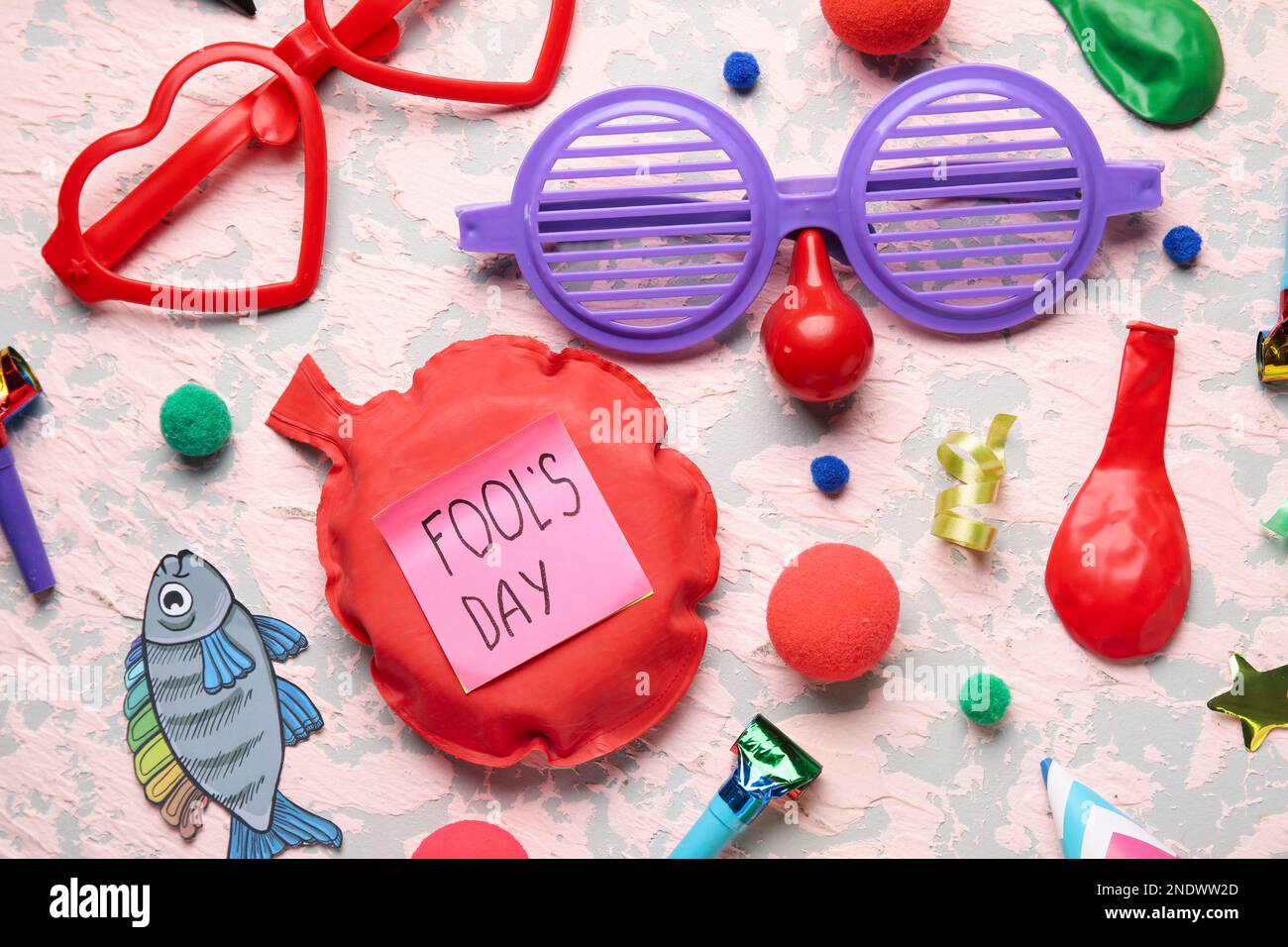 Sticky paper with text FOOL'S DAY, whoopee cushion and party decor on grunge background Stock Photo