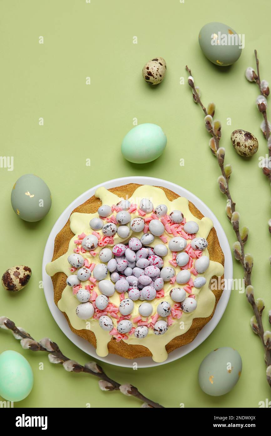 Composition with tasty Easter cake, eggs and willow branches on green background Stock Photo