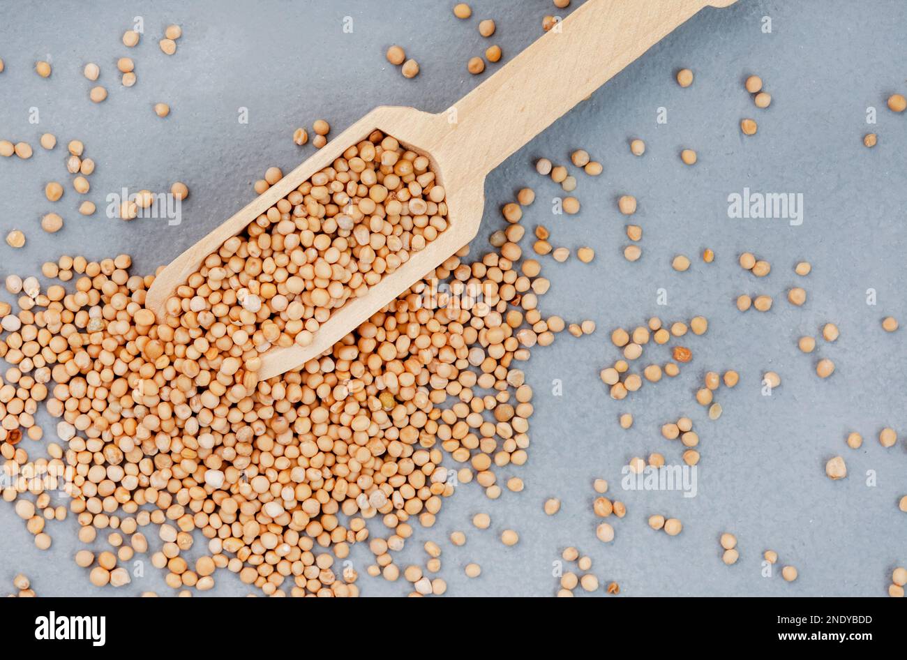 Yellow mustard seeds with scoop on mottled grey surface Stock Photo Alamy