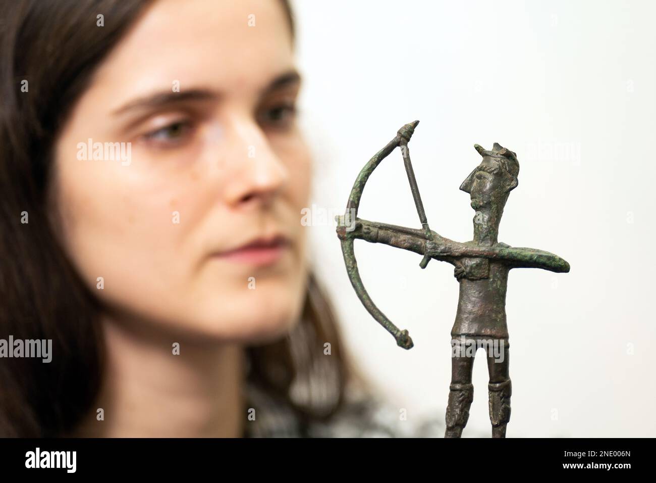 Olivia Maguire inspects a bronze figurine of an archer (1000???700 BCE