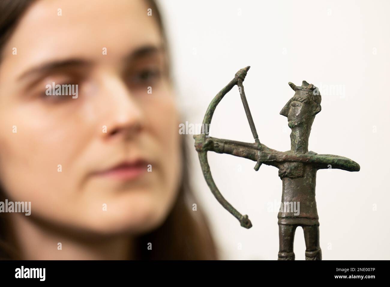 Olivia Maguire inspects a bronze figurine of an archer (1000???700 BCE