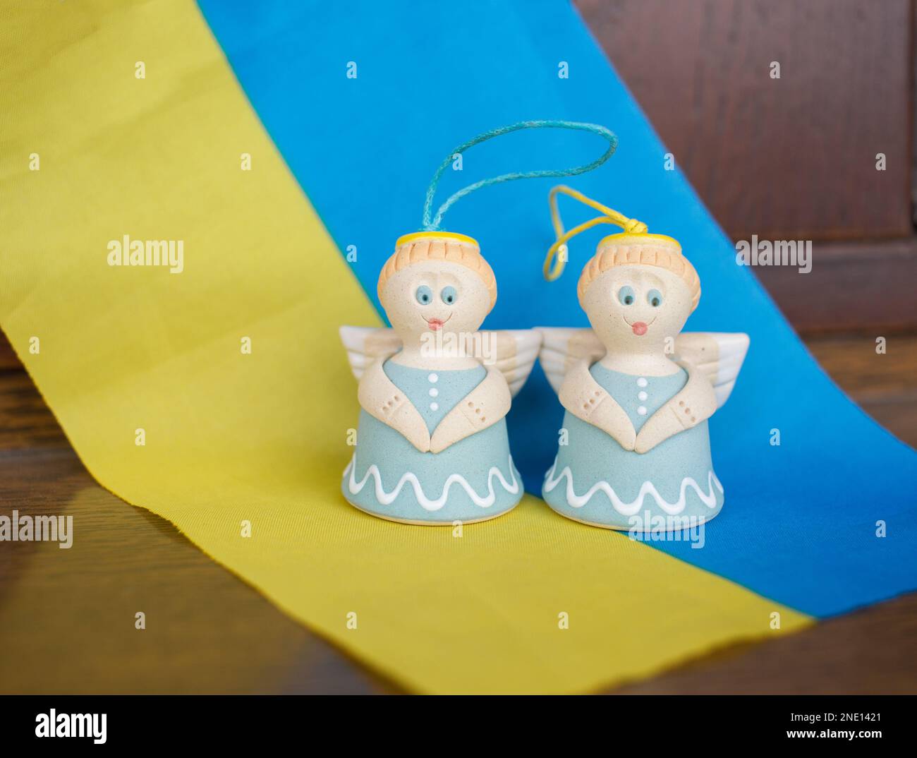 Two souvenir angels on the blue and yellow Ukrainian flag. Pray for peace for Ukraine. Faith and hope. Stop the war. Blessed memory of the fallen sold Stock Photo