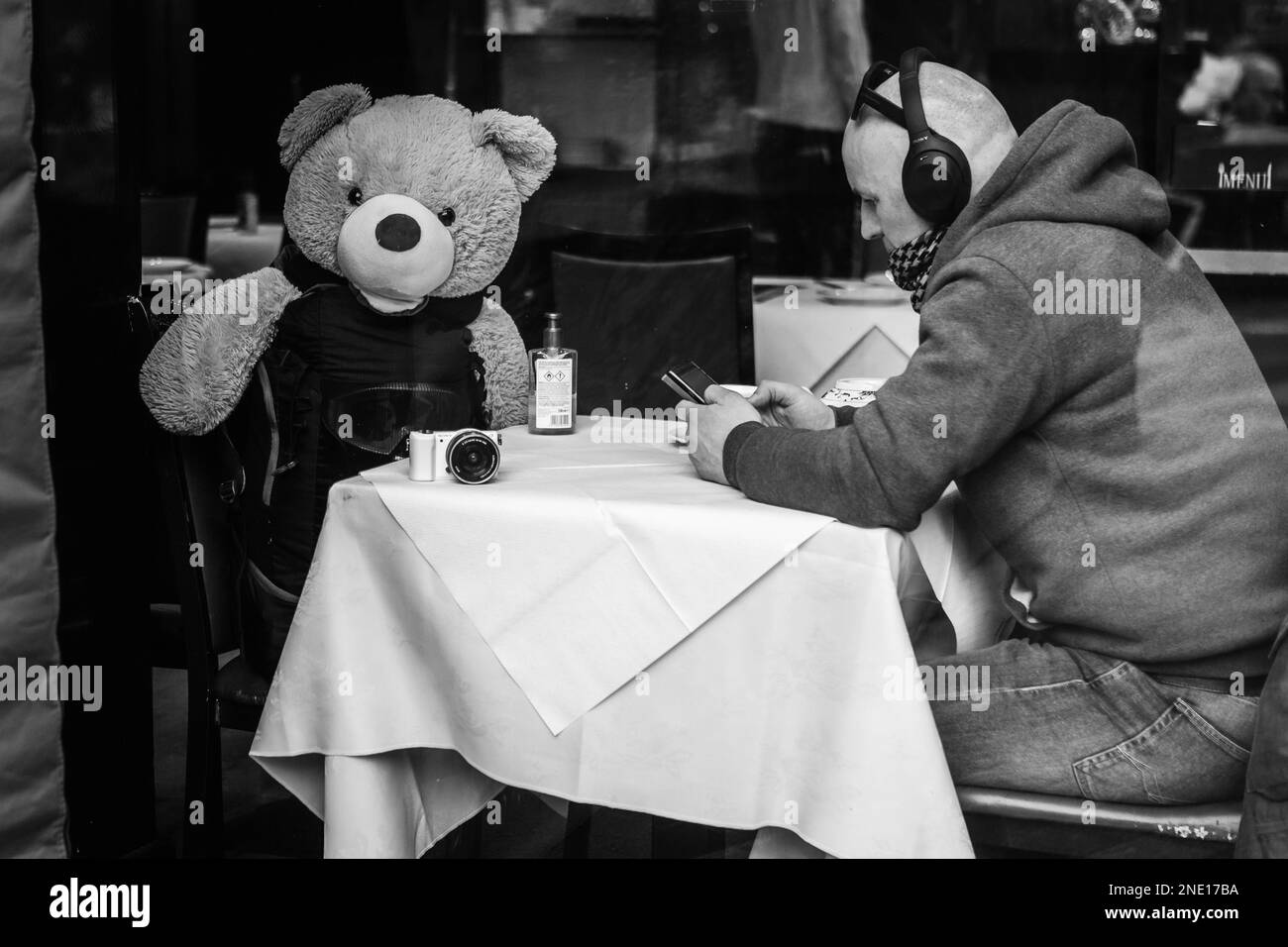 A black and white image of a teddy bear, and a diner at a chinese restaurant in London's chinatown. Stock Photo