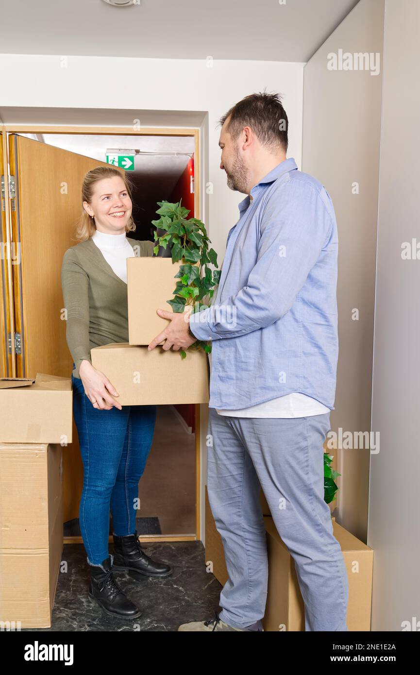 Happy couple moving in their new apartment carrying cardboard boxes ...