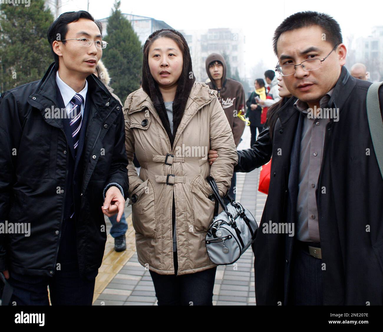 Li Xuemei, center wife of Zhao Lianhai, leaves the court house with her lawyers Li Fangping, left, and Peng Jian after her husband trial case in Beijing, Tuesday, March 30, 2010. Zhao Lianhai, who organized a support group for parents of children sickened in one of China's worst food safety scandals pleaded not guilty Tuesday to charges of inciting social disorder, his lawyer said. (AP Photo/Andy Wong) Stock Photo