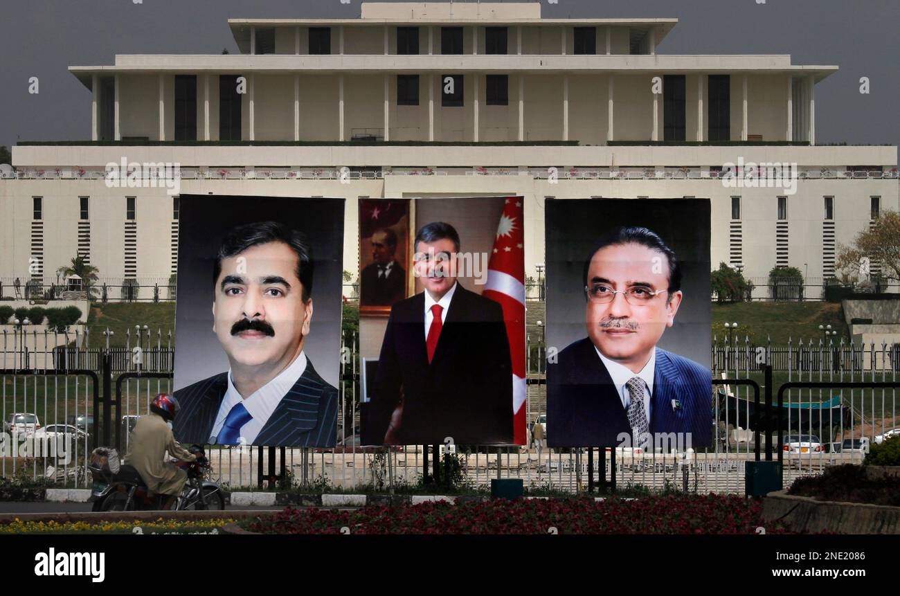 A motorcyclist drives past huge portraits of Turkish President 