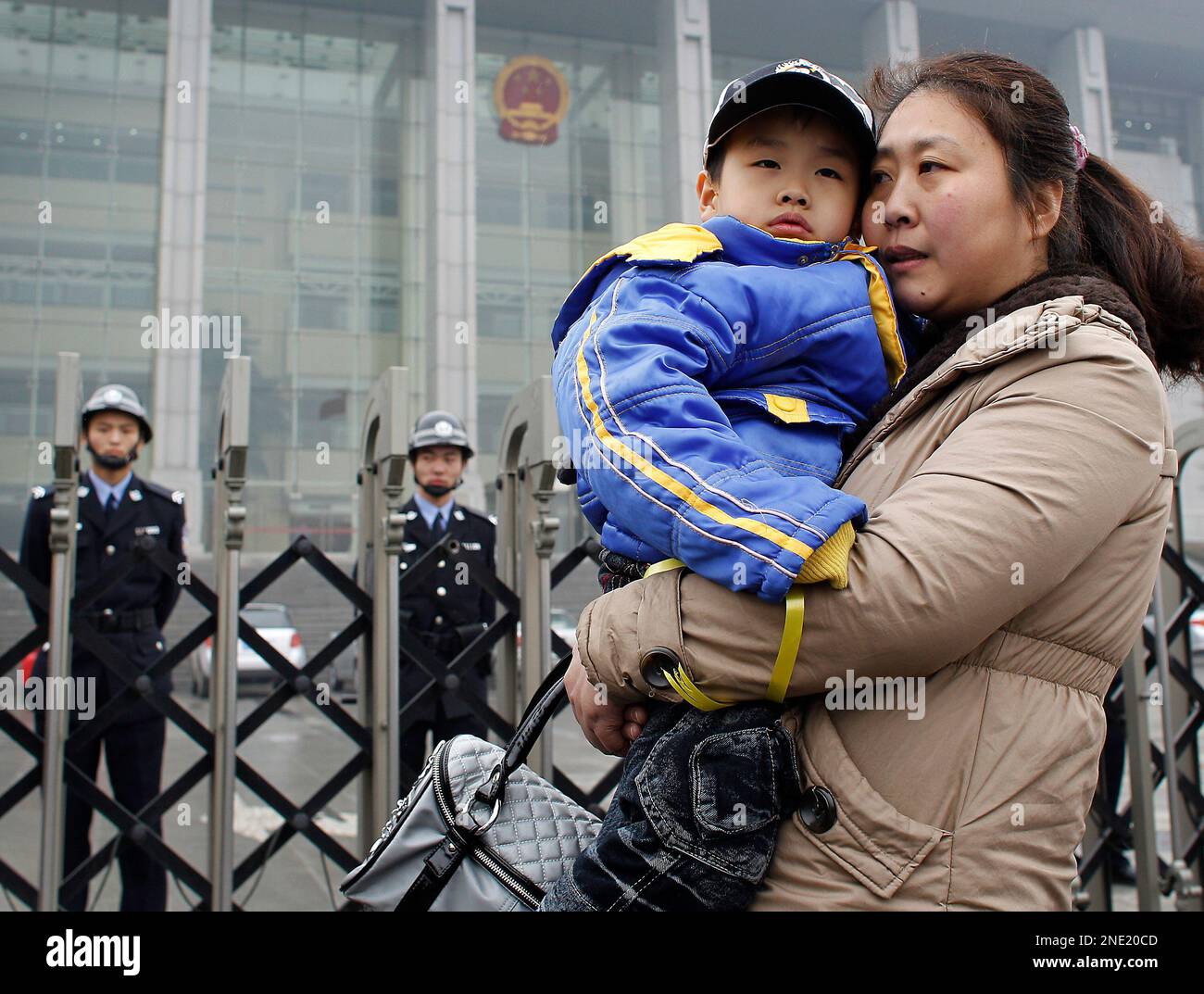 Li Xuemei, wife of Zhao Lianhai, with her son stand outside a court house as she is not allowed to enter to see her husband during a trial case in Beijing, Tuesday, March 30, 2010. Zhao Lianhai, who organized a support group for parents of children sickened in one of China's worst food safety scandals pleaded not guilty Tuesday to charges of inciting social disorder, his lawyer said. (AP Photo/Andy Wong) Stock Photo